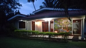 A house with a tiled roof, a front porch, and a well-maintained lawn. - Onix Villa (Galle)