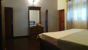 A bedroom with a bed, a dresser, a mirror, and a window with curtains. - Onix Villa (Galle)