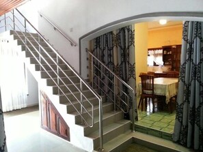 A staircase with metal railings leading to a dining area with a table and chairs.
