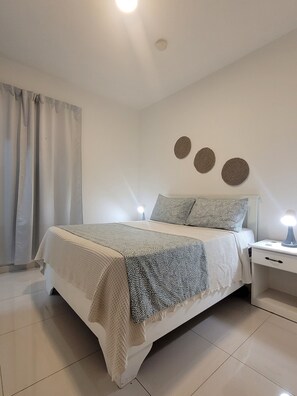 Een keurig opgemaakte slaapkamer met een bed, nachtkastjes en een nachtkastje.