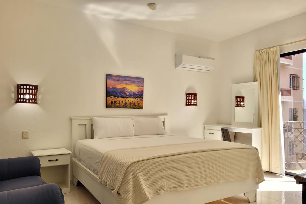 Ein Schlafzimmer mit einem Bett, Nachttischen, einem Schreibtisch und einem Sessel.