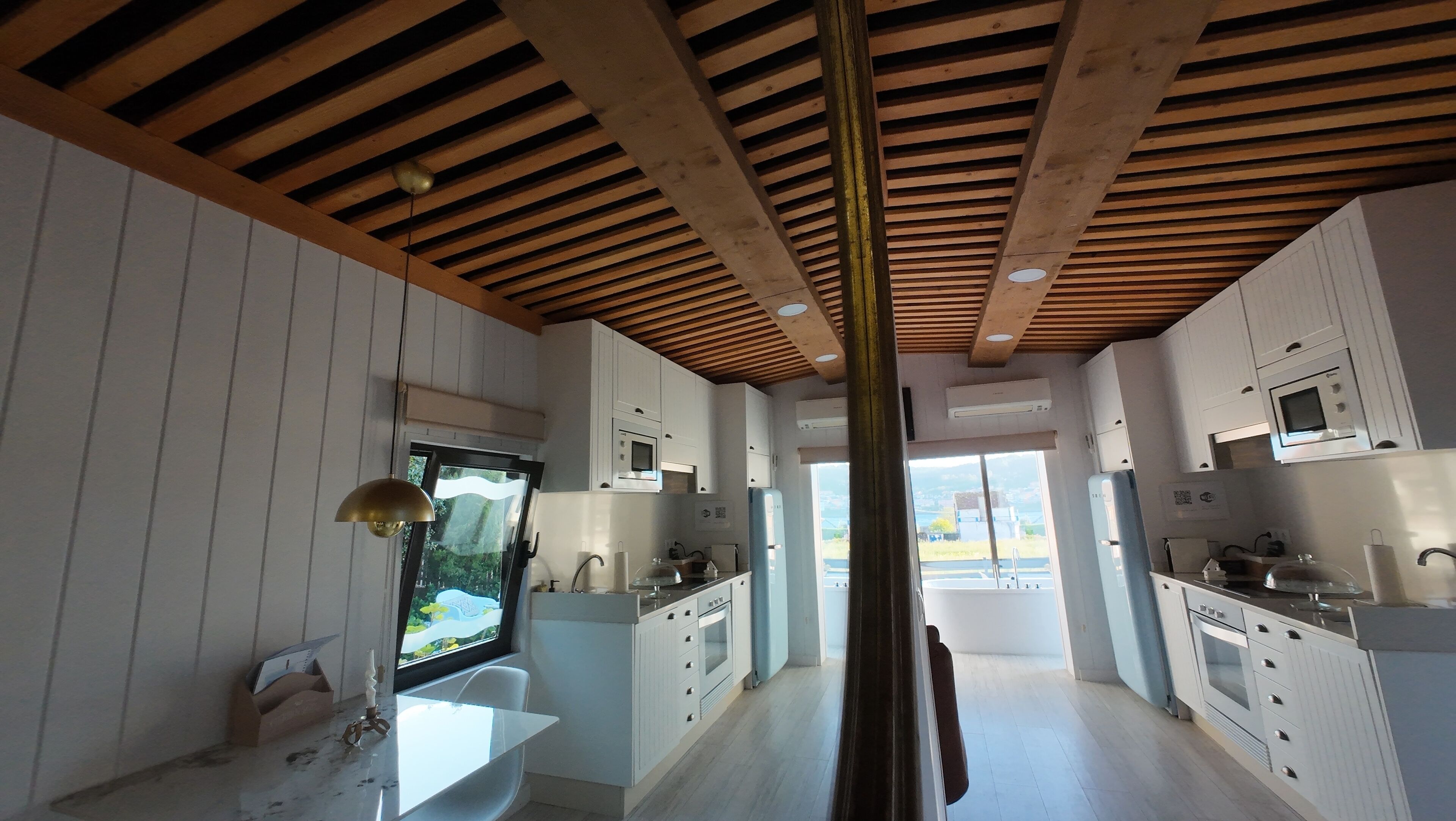 A modern kitchen with white cabinetry, a central island, and a wooden ceiling.