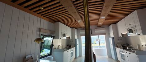 A modern kitchen with white cabinetry, a central island, and a wooden ceiling.