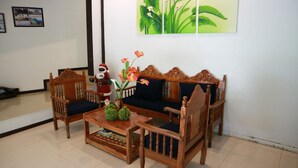 Una sala de estar con un sofá, dos sillones, una mesa de centro y una planta decorativa.