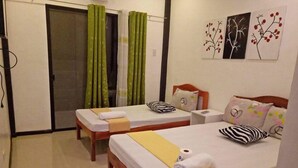 Habitación de hotel con dos camas individuales, cabecero de madera, una mesita de noche pequeña y una pared con tres obras de arte enmarcadas.