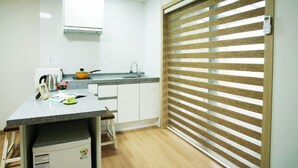 Une cuisine compacte dotée d’un plan de travail en granit, d’une bouilloire, d’une petite cuisinière et d’un évier.