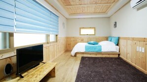Une petite pièce agréable, avec un lit, un téléviseur posé sur un meuble en bois et une fenêtre équipée de stores.