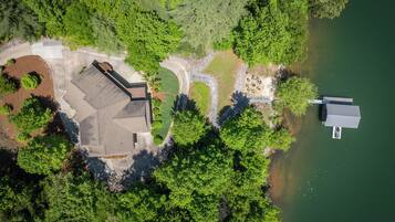 An aerial view of a property with a large house, a dock, and a lake.