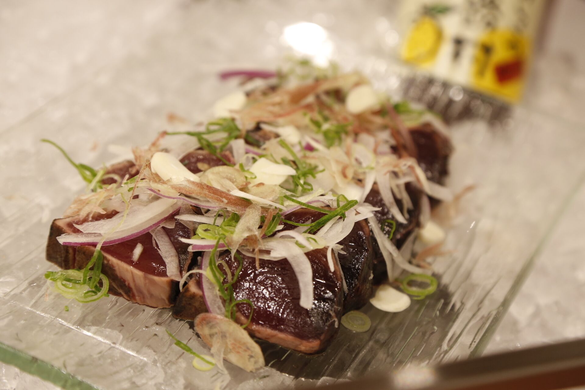 Un plat composé de tranches de viande, d’oignons et d’oignons verts, servi dans une assiette.
