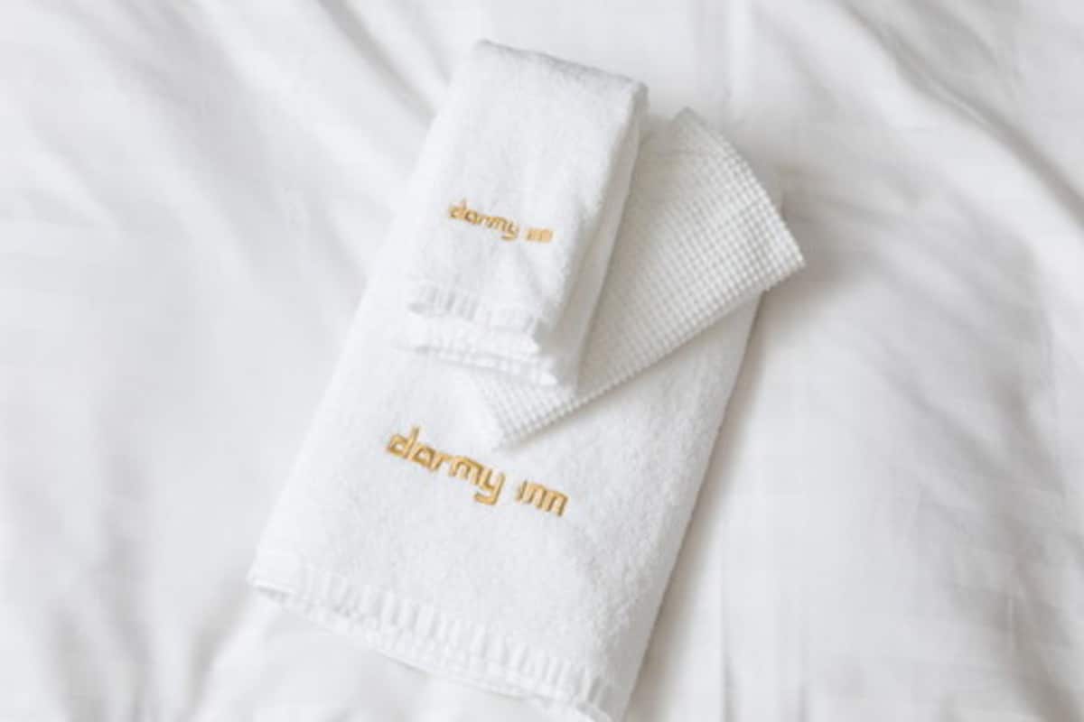 A neatly folded white towel with 'darmy inn' embroidered in gold lettering.