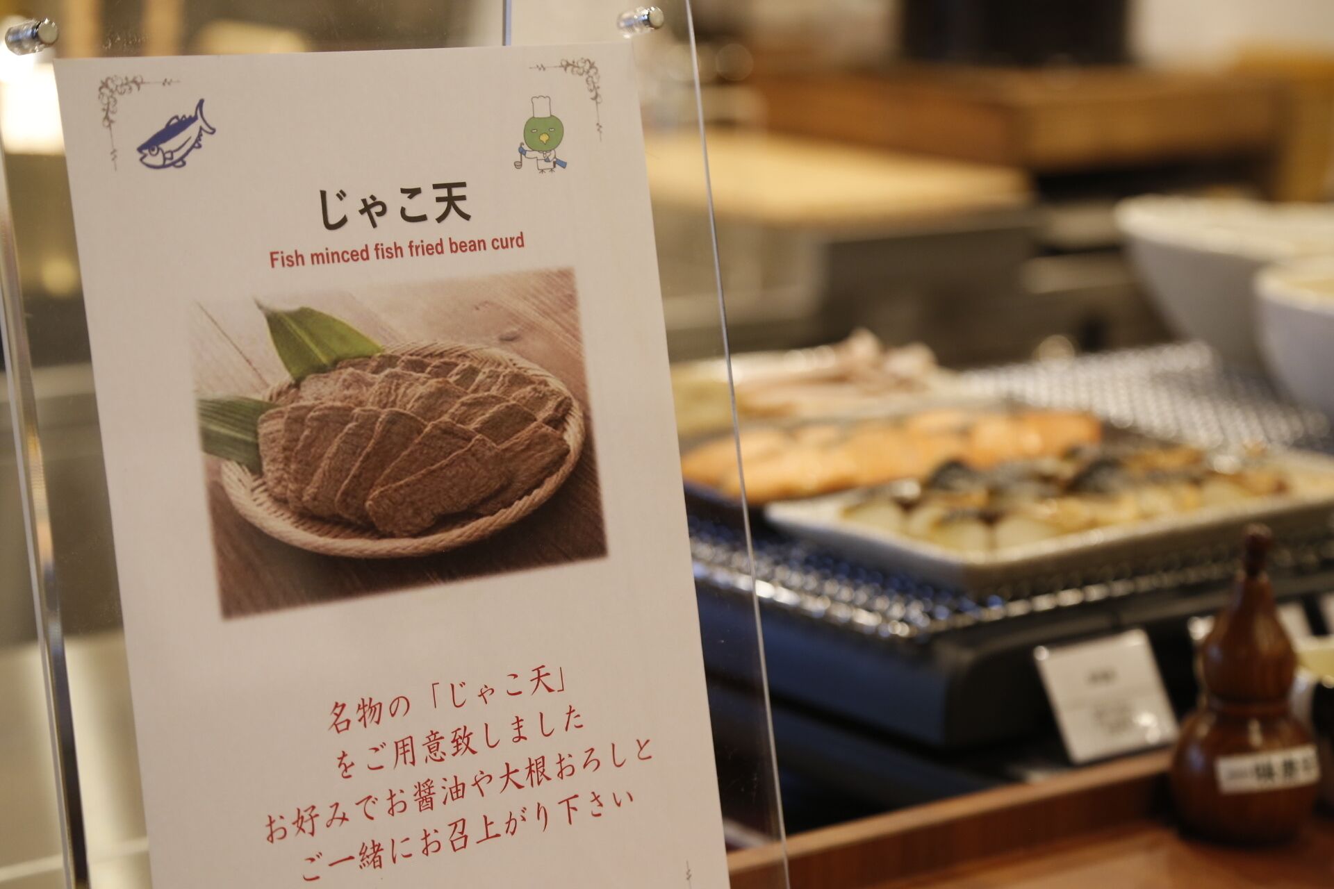 A menu board with Japanese text and a picture of a fish dish.