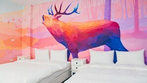A hotel room with a large, colorful deer mural on the wall, two white beds, and a nightstand with drawers.