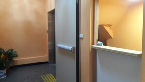 A hallway with a door, a small shelf, and a potted plant.