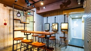 A bar area with stools, a long table, and multiple hanging lights.