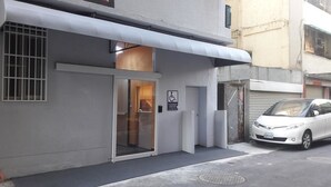 A building with a glass door entrance, a wheelchair accessibility sign, and a parked car.