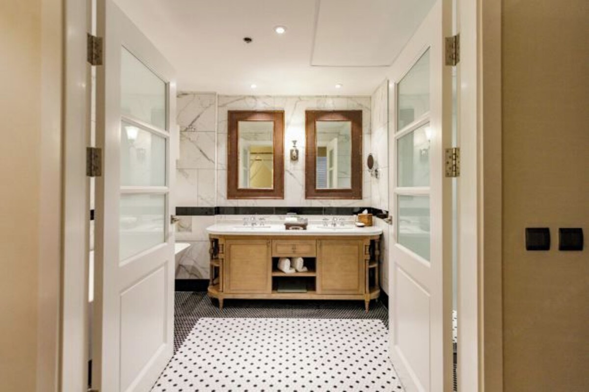 Une salle de bain moderne avec un meuble-lavabo double, un pare-feu en marbre et un carrelage à pois.
