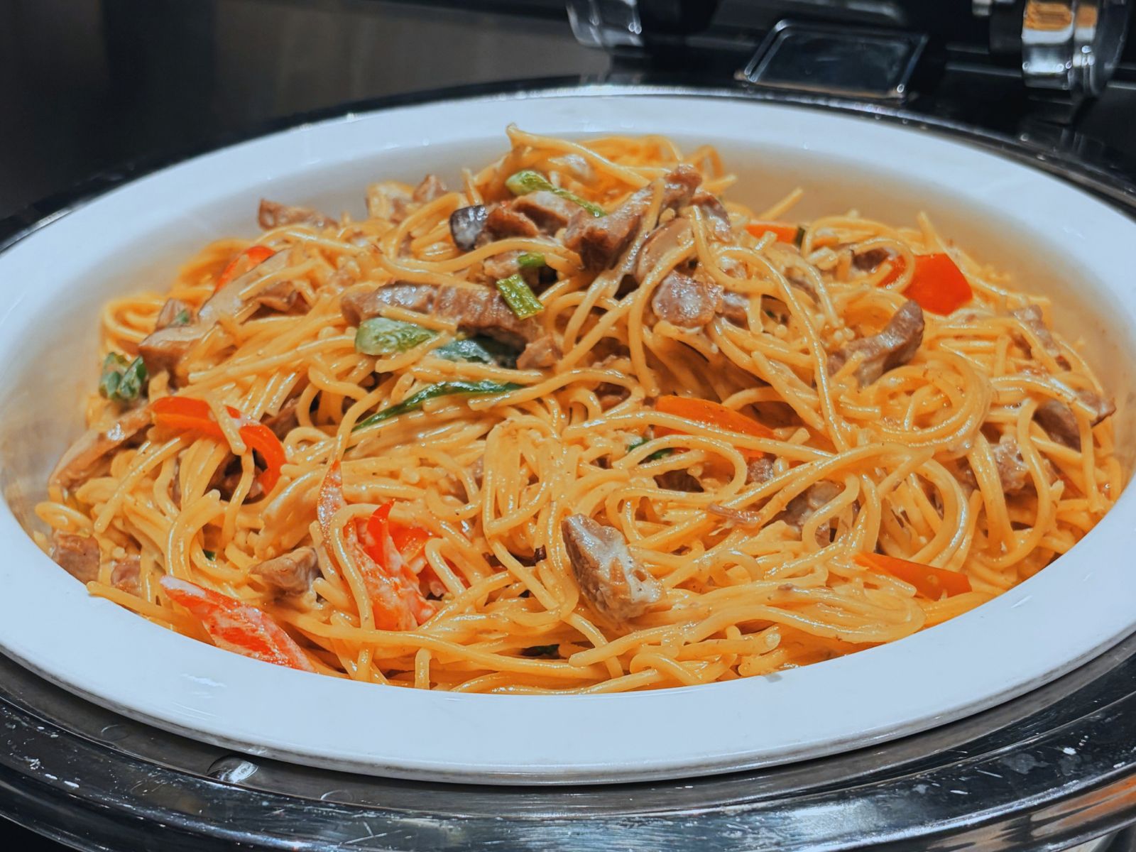 A bowl of stir-fried noodles with vegetables and meat.