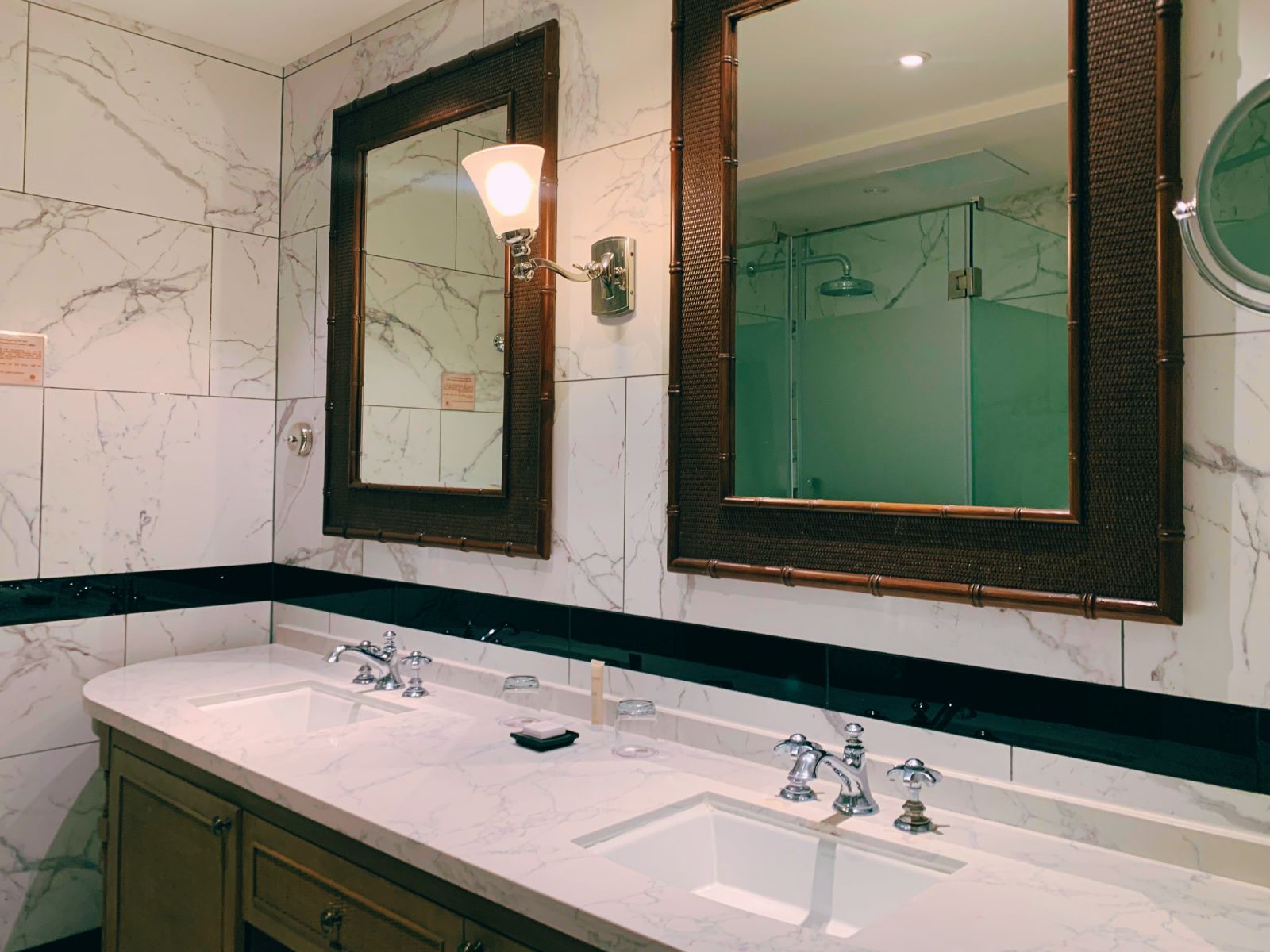 A bathroom with two mirrors, a vanity with a sink, and a shower area.