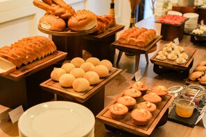 Un buffet proposant une variété de produits de boulangerie, notamment du pain, des petits pains et des muffins.