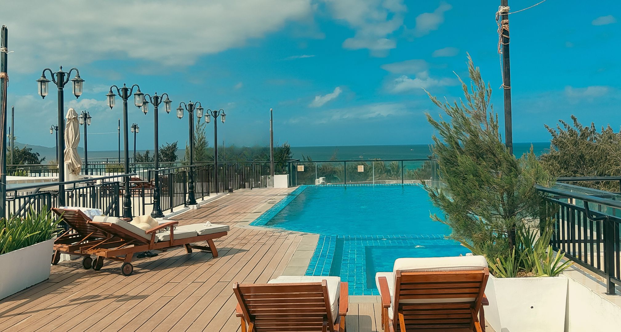 A pool area with lounge chairs and a view of the sea.