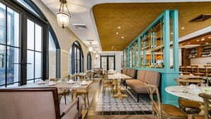 L’intérieur du restaurant se caractérise par de hauts plafonds, de grandes fenêtres et une variété d’aménagements, notamment des tables et des banquettes.