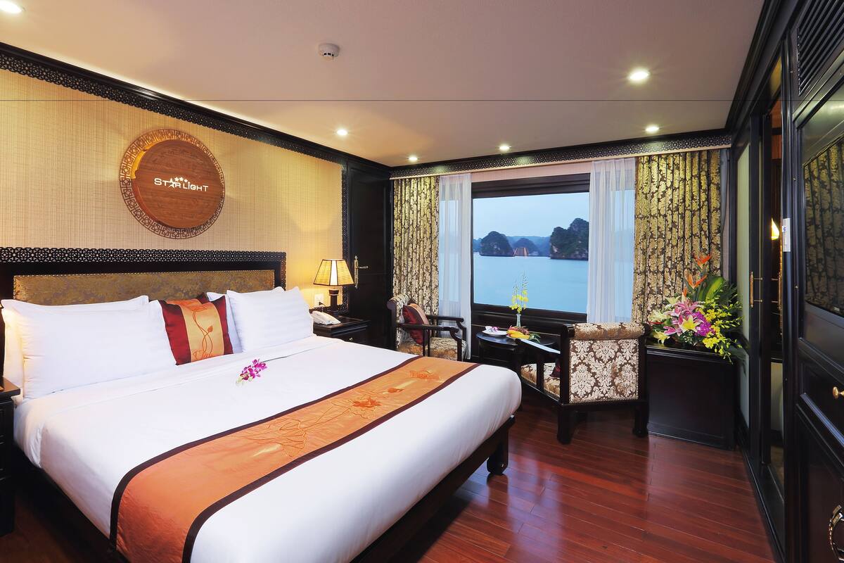 A hotel room with a large bed, a desk, and a view of a body of water.