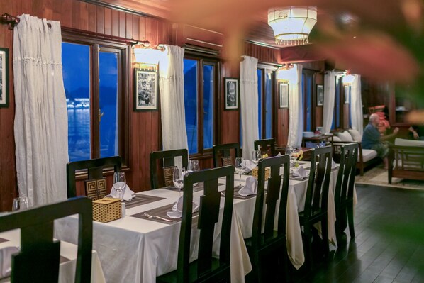 Un restaurante con mesas preparadas para comer, paredes con paneles de madera y vistas al agua.