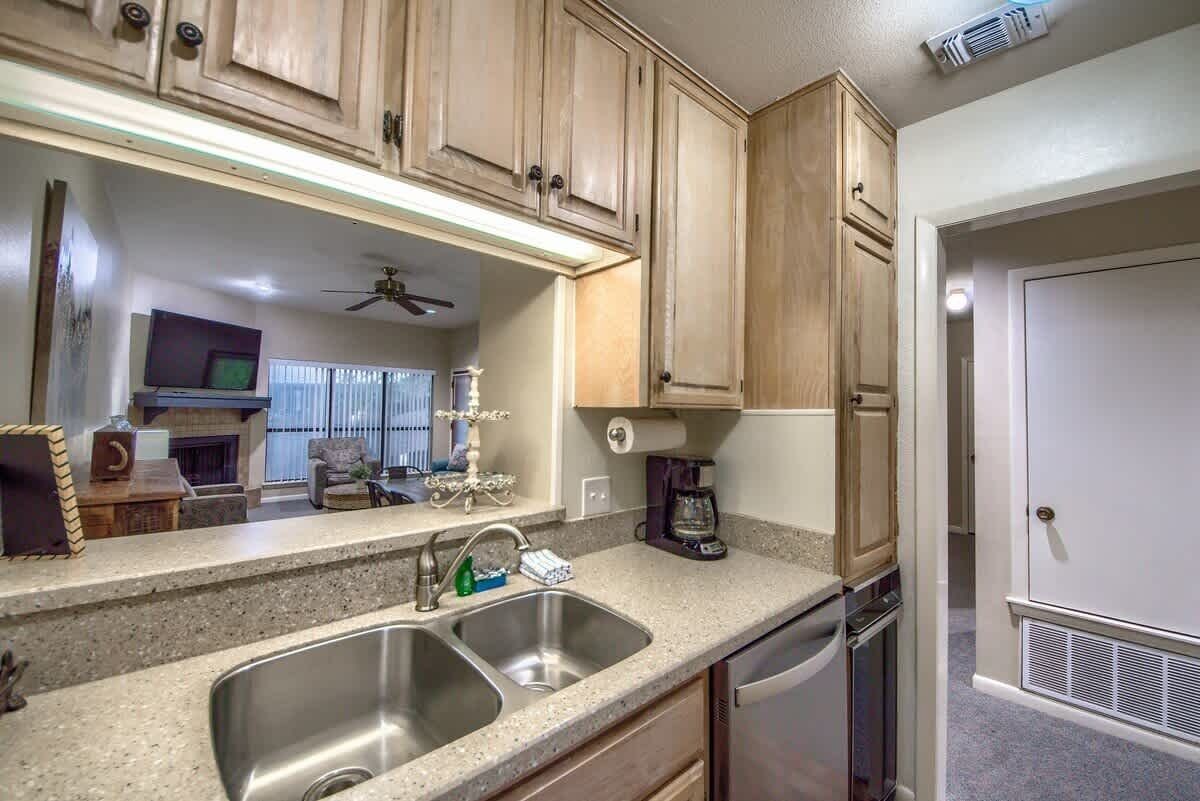 A kitchen with granite countertops, stainless steel sink, wooden cabinets, and a dishwasher.