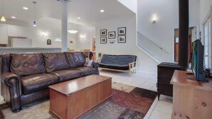A spacious living area with a leather sofa, a wooden coffee table, and a staircase leading to an upper level.