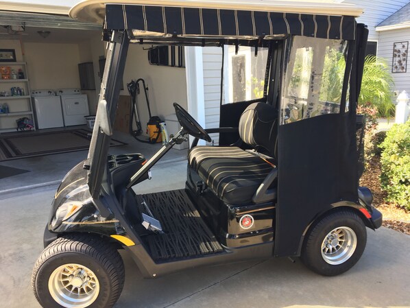 A golf cart parked in a garage with a laundry area in the background.