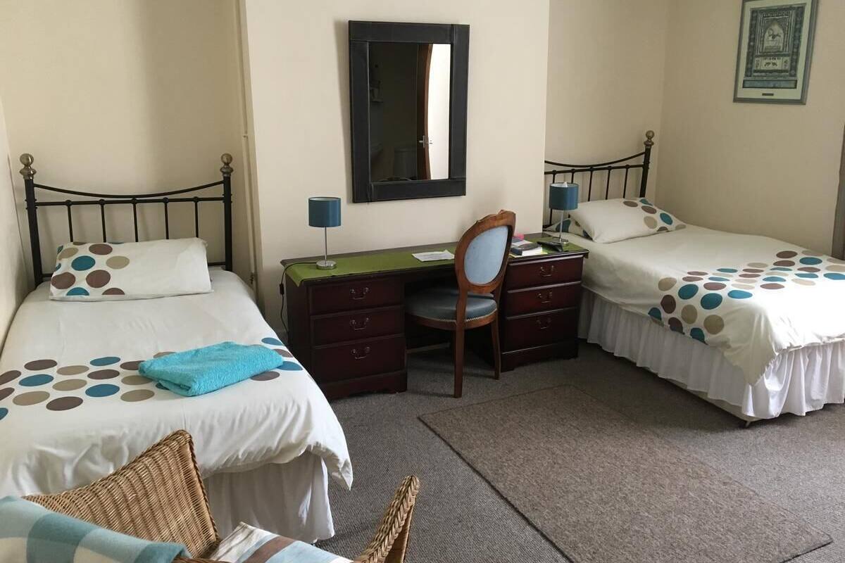 Een slaapkamer met twee bedden, een bureau, een stoel en een klein tafeltje.