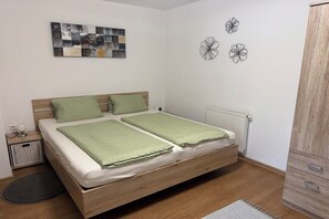 Un dormitorio con una cama doble, un radiador, un armario, una mesita de noche pequeña y una obra de arte en la pared.