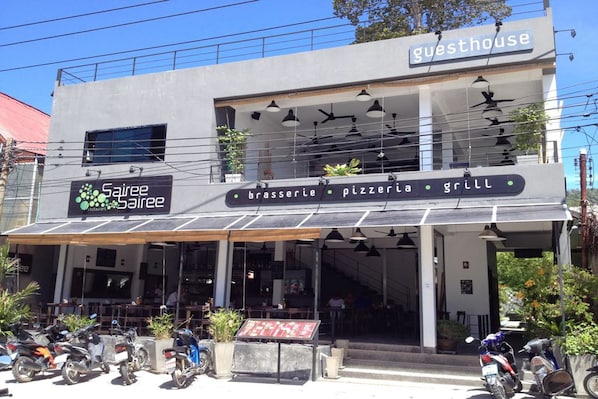 A guesthouse with a sign indicating it offers brasserie, pizzeria, and grill services.