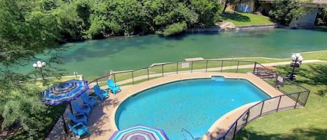 A swimming pool with a surrounding deck, a slide, and a view of a river.