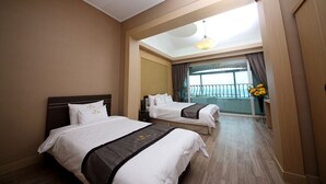 Een hotelkamer met twee bedden, een balkon en uitzicht, plus een plafondlamp.