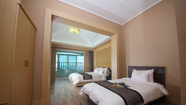 Een hotelkamer met twee bedden, een kledingkast, een balkon en uitzicht.
