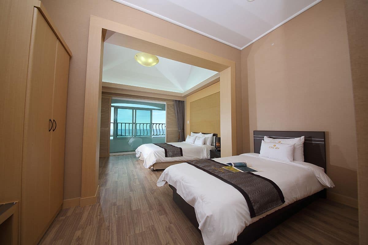 Une chambre d’hôtel avec deux lits, une armoire, un balcon et une vue sur l’extérieur.