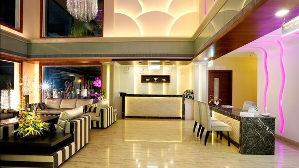 Un vestíbulo de hotel moderno con mostrador de recepción, zona de estar e iluminación decorativa.