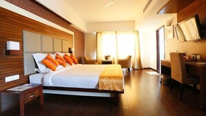 Habitación de hotel con una cama grande, un escritorio, una silla, un televisor y un ventilador de techo.