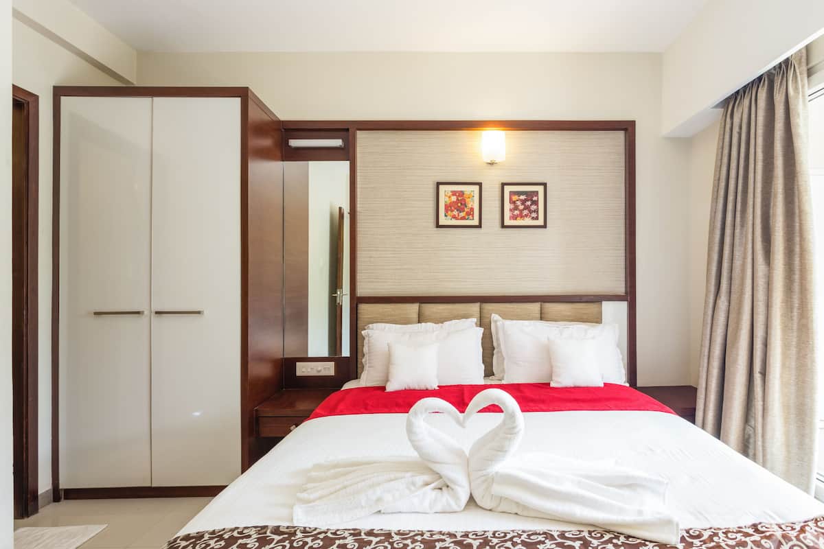 A hotel room with a large bed, a wardrobe, and two framed pictures on the wall.
