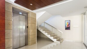 Ein moderner Aufzug, eine Treppe und ein gerahmtes Kunstwerk an der Wand.