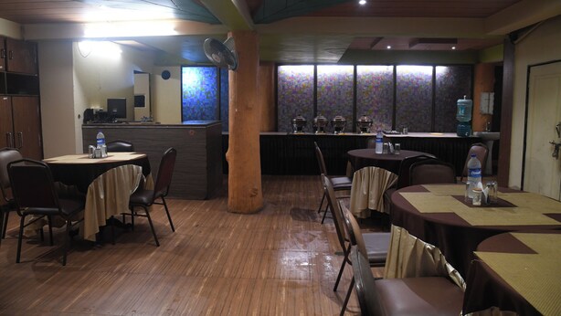 A restaurant with round tables, chairs, a bar area, and a large water dispenser. - Hill Forest Resort Lonavala (Mawal)