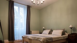Una camera da letto con un letto, due comodini, un termosifone e una finestra con tende.