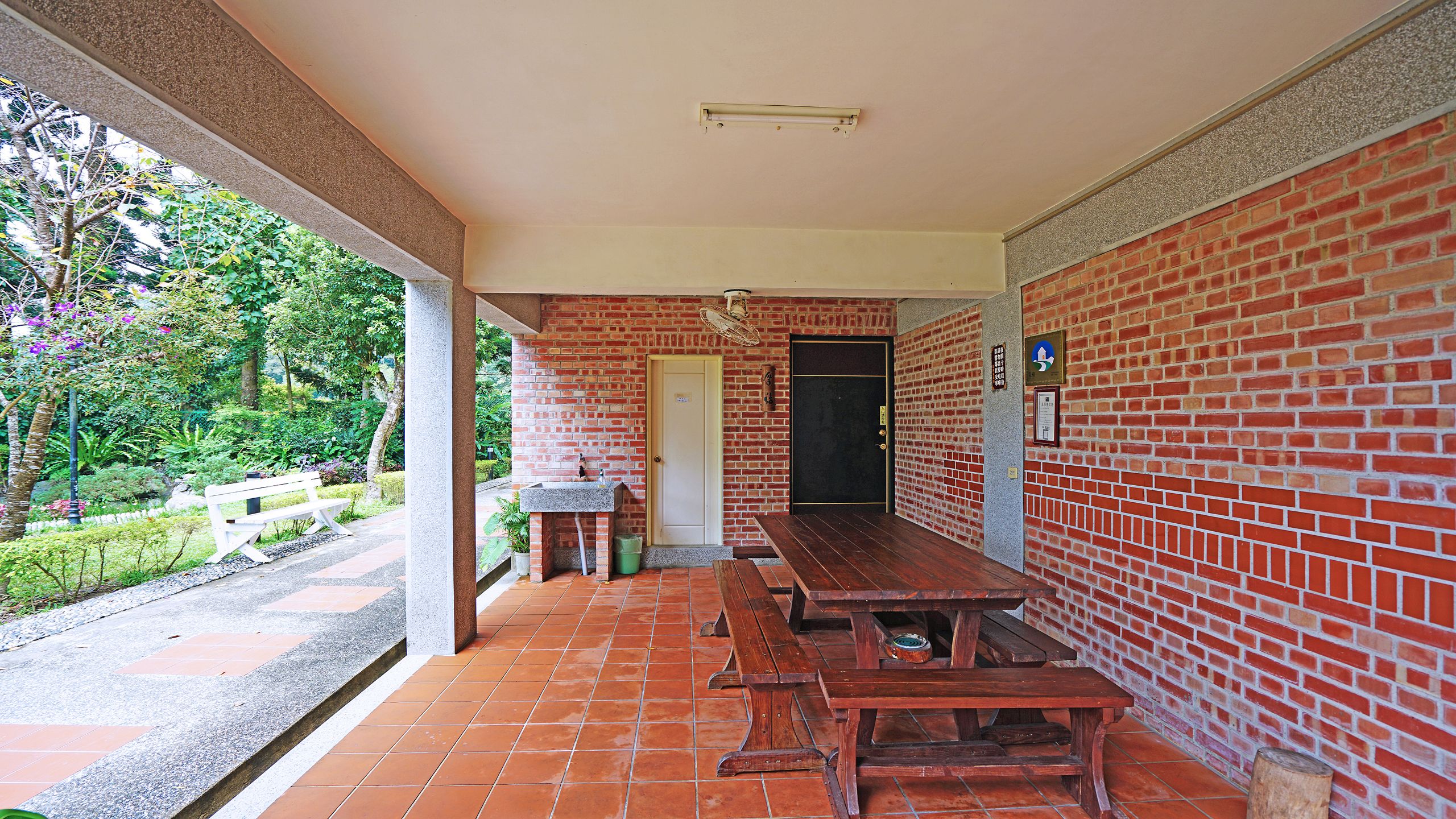 A covered patio with brick walls, a door, and a bench.