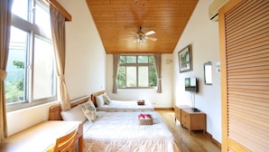 Un dormitorio con dos camas, ventilador de techo, televisión y ventana con cortinas.
