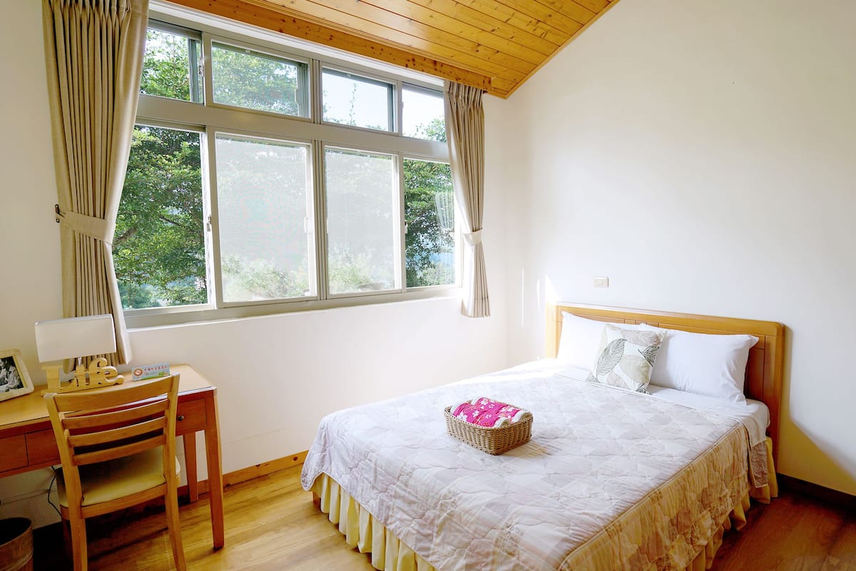 Um quarto com uma cama, uma escrivaninha e uma cadeira.