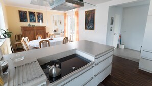 Una cocina moderna con una isla central, un comedor con mesa y sillas, y vistas al comedor a través de un separador de vidrio.