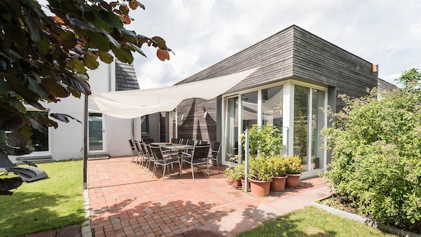 Una casa moderna con un patio, una mesa de comedor y plantas en macetas.
