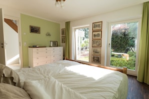 Ein Schlafzimmer mit einem großen Bett, einem Schminktisch und einem Fenster mit Gartenblick.