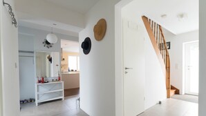 Un interior moderno con una escalera blanca, una puerta blanca y un pasillo que conduce a una zona de cocina.